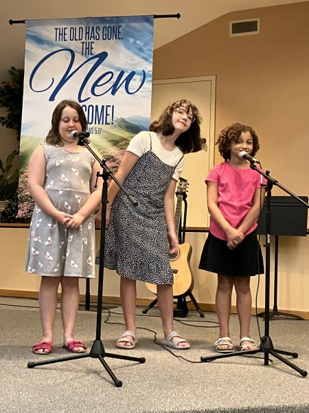 Three girls singing on a stage with microphones