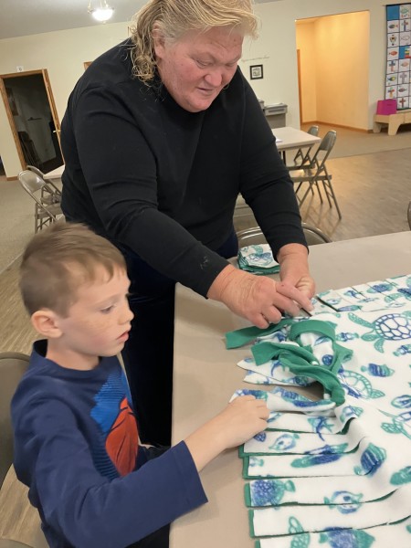 A woman demonstrating a fabric project to a boy